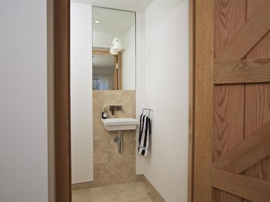 A small bathroom with a wall-mounted sink a mirror and a towel on a rack at The Milking Shed in Bantham
