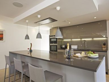 A modern kitchen with a large island and three pendant lights above at The Milking Shed in Bantham