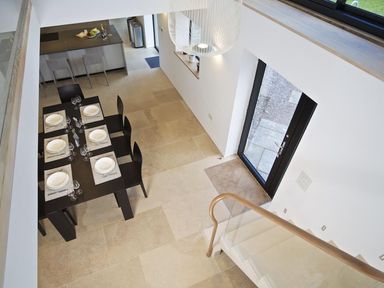 A dining area with a black table set for six near a staircase and glass door at The Milking Shed in Bantham
