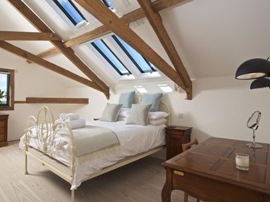 A bedroom with a bed under skylights and wooden beams at The Milking Shed in Bantham