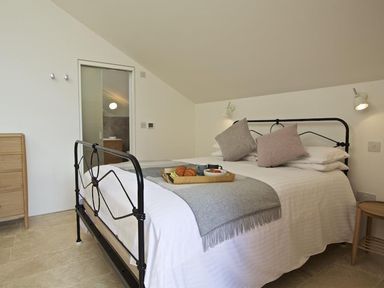 A bedroom with a metal bed frame and breakfast tray on the bed at The Milking Shed in Bantham