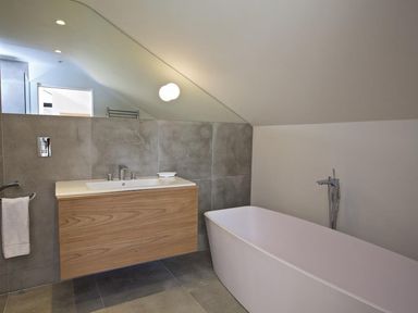 A bathroom with a freestanding bathtub and a sink with wooden cabinet at The Milking Shed in Bantham