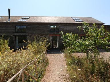 A building with windows and a door in a garden at The Milking Shed in Bantham