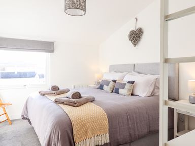 A bedroom with a bed covered in gray and yellow bedding and towels on top at Sea Breeze in Porthmadog