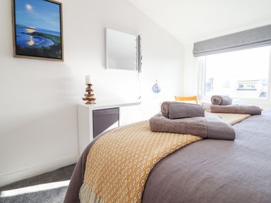 A bedroom with towels on a bed a framed picture and a mirror on the wall at Sea Breeze in Porthmadog