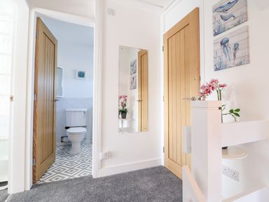 A hallway with a mirror on the wall and an open door showing a bathroom with a toilet Sea Breeze Porthmadog