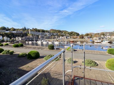 A harbor with boats on water and houses on a hill in the background at Sea Breeze in Porthmadog