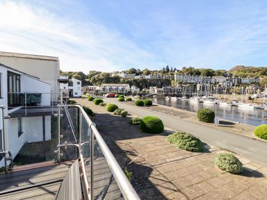 A view of a harbor with boats and houses seen from a balcony with glass railing at Sea Breeze in Porthmadog