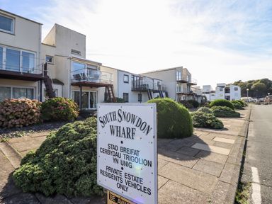 A residential area with white buildings and balconies along a paved sidewalk with bushes at South Snowdon Wharf