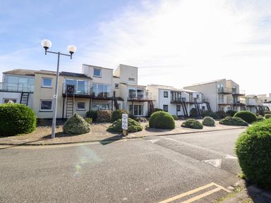 A row of modern white residential buildings with balconies bushes and street lamps at Sea Breeze in Porthmadog