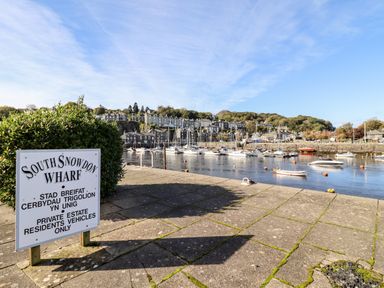 A sign for South Snowdon Wharf beside a harbor with boats and buildings in the background at Sea Breeze in Porthmadog