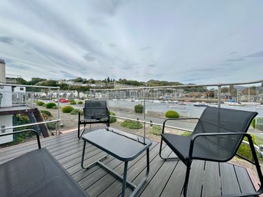 A balcony with black chairs and a table overlooking boats on the water at Sea Breeze in Porthmadog