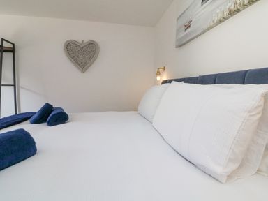 A bedroom with a bed with white bedding and blue towels on a bed at Robins Downs in Ilfracombe