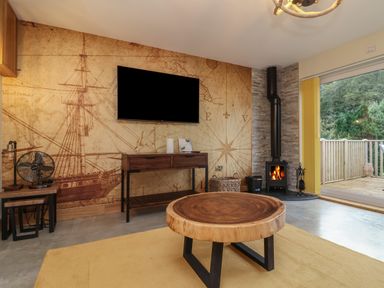 A living room with a wooden coffee table yellow rug fireplace and nautical map wallpaper at Robins Downs Ilfracombe