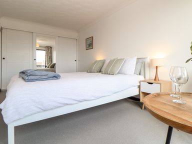 A bedroom with a bed white frame and linens pillows wooden side table lamp and wardrobe with sliding doors at Chi an Vre in Newlyn