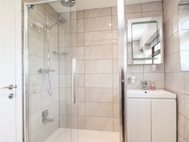 A bathroom with a glass shower enclosure and a white vanity unit with a mirror above at Chi an Vre in Newlyn