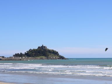 A coastal view with a castle on a hill and a person kite surfing at Chi an Vre in Newlyn