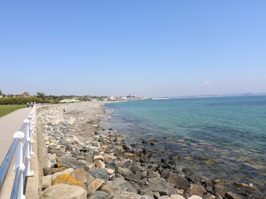 A rocky shoreline with a paved walkway and railings beside the sea at Chi an Vre in Newlyn