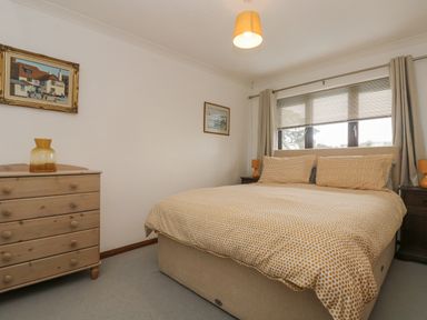 A bedroom with a double bed wooden dresser and two bedside tables with lamps at Chi an Vre in Newlyn