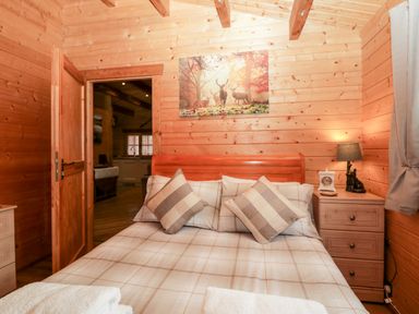 A bedroom with a wooden bed and checked pillows with a bedside table lamp at Ballinorig Lodge in Cleator Moor