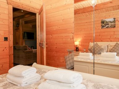 A bedroom with wooden walls and a bed with folded towels at Ballinorig Lodge in Cleator Moor