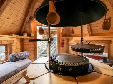 An interior wooden cabin room with a round grill and wooden benches at Ballinorig Lodge in Cleator Moor