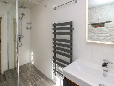 A bathroom with a walk-in shower a towel radiator and a sink at Ty Len in St Davids
