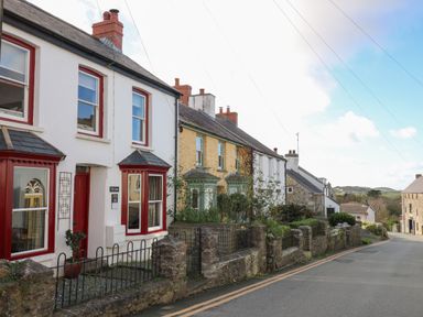 A street view of houses with stone walls and gardens at Ty Len in St Davids