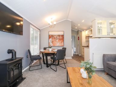 A dining area with a round table and four chairs next to a kitchen and living space at Squirrels Nook Waterside Wood 19 White Cross Bay near Windermere