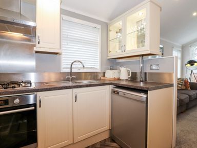 A kitchen with white cabinets a sink a dishwasher and a kettle at Squirrels Nook Waterside Wood 19 White Cross Bay near Windermere