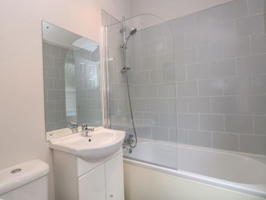 A bathroom with a sink cabinet toilet bathtub with shower and glass screen at Squirrels Nook in Waterside Wood 19 White Cross Bay near Windermere