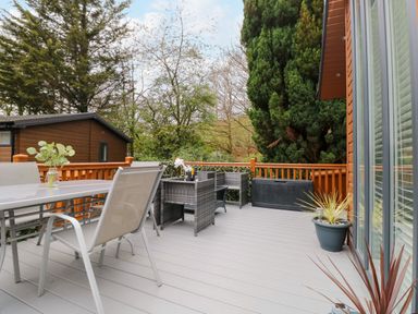 An outdoor deck with seating tables chairs plants and trees at Squirrels Nook in Waterside Wood 19 White Cross Bay near Windermere