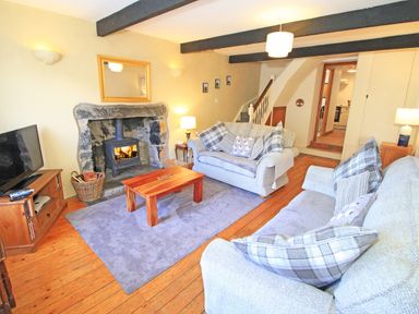 A living room with two sofas a wooden coffee table a fireplace and a television at Hafan Cottage in Beddgelert