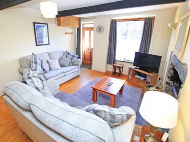 A living room with sofas a wooden coffee table a television and a fireplace at Hafan Cottage in Beddgelert
