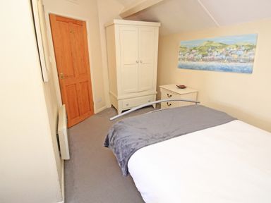 A bedroom with a bed a white wardrobe a white chest of drawers and a painting on the wall at Hafan Cottage in Beddgelert