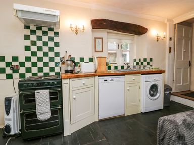 A kitchen with a stove, dishwasher, washing machine, toaster, kettle, and sink at Gardeners Cottage Millom Cumbria