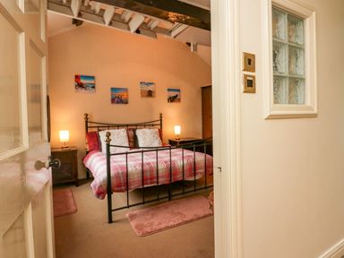 A bedroom with a metal bed frame bedside tables with lamps and framed pictures on the wall at Gardeners Cottage in Millom Cumbria
