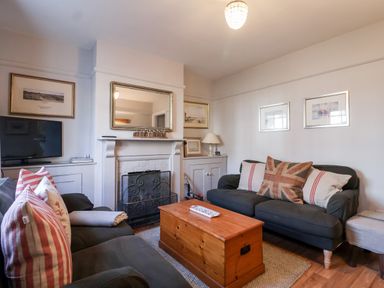 A living room with two sofas a wooden chest coffee table a fireplace and a television at 3 Albion Cottages Walberswick