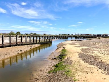 A river with a wooden fence along the bank and a sandy shore at 3 Albion Cottages in Walberswick