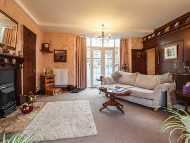 A living room with a sofa coffee table fireplace and large windows at The Barn in Middleton near Ponteland