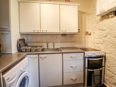 A kitchen with washing machine sink cabinets stove and kettle at The Barn in Middleton near Ponteland