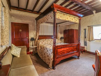 A bedroom with a four poster bed a sofa a wardrobe and a window at The Barn in Middleton near Ponteland