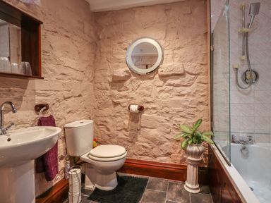 A bathroom with a toilet sink bathtub and a plant on a pedestal at The Barn in Middleton near Ponteland