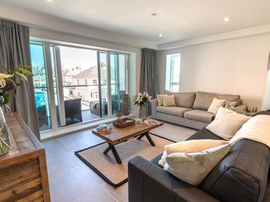 A living room with two sofas a wooden coffee table and sliding glass doors leading to a balcony at 31 Cliff Edge in Newquay
