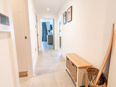 A hallway with two framed pictures on the wall a wooden bench with wicker baskets and a woven basket holding a wooden item at 31 Cliff Edge in Newquay
