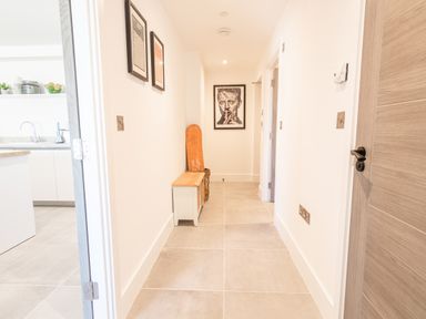 A hallway with tiled floor a bench a wooden door and framed pictures on the walls at 31 Cliff Edge in Newquay