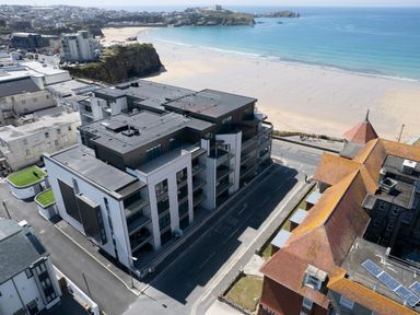 A coastal town with modern and older buildings near a sandy beach and ocean at 31 Cliff Edge in Newquay