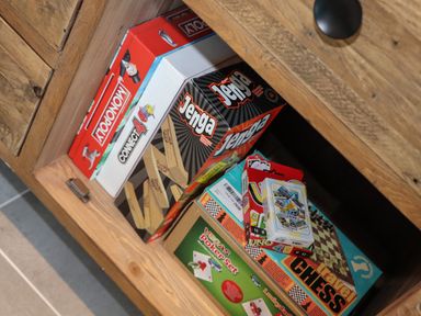 A wooden drawer with board games including Monopoly Connect 4 Jenga travel chess and poker set at 31 Cliff Edge in Newquay