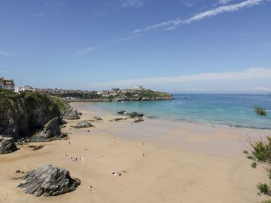 A sandy beach with rocks and people near the ocean and houses on cliffs at 31 Cliff Edge in Newquay