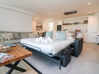 A living room with a sofa bed open and pillows towels on it at 31 Cliff Edge in Newquay